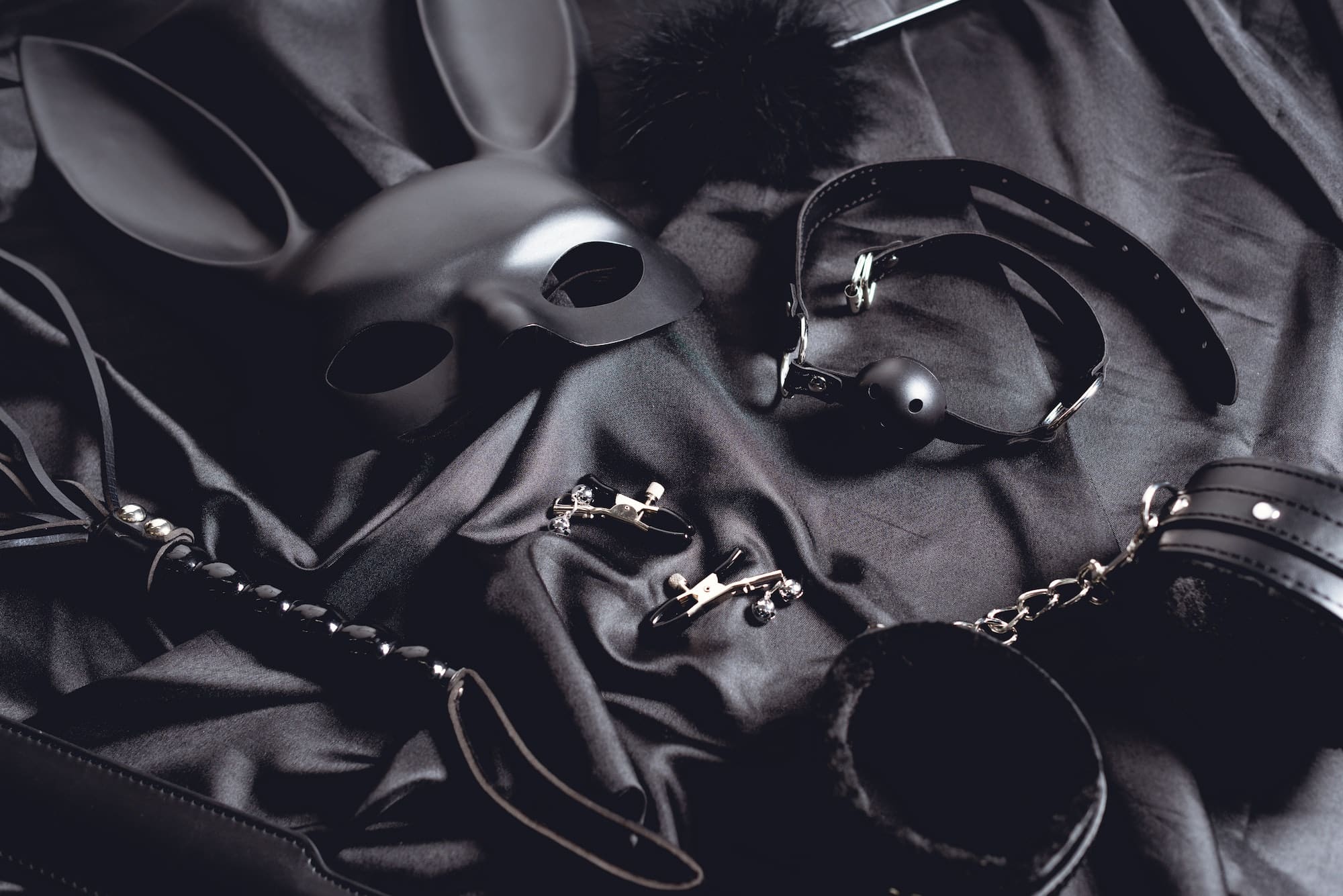 rabbit mask near sex toys on black silk fabric